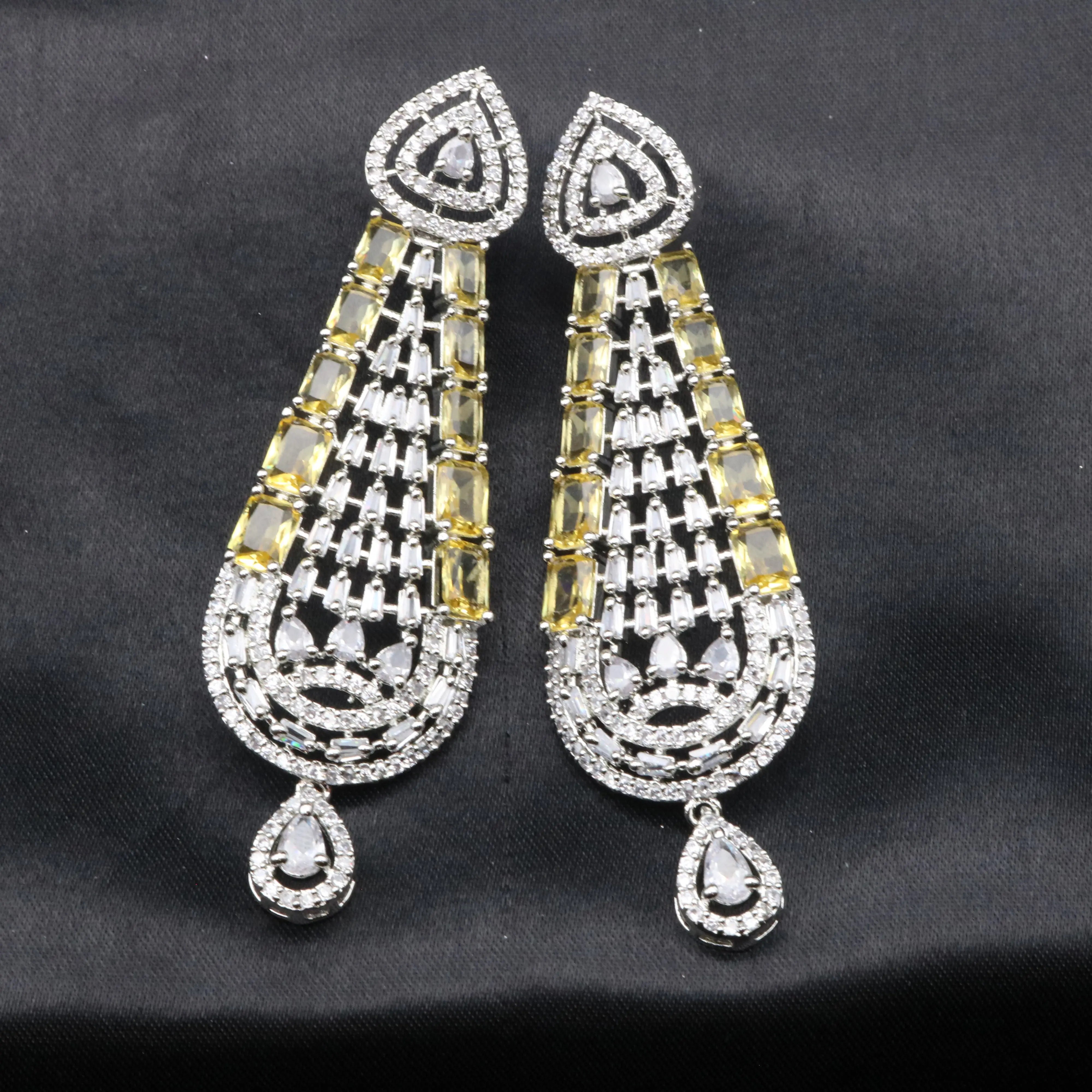 Pair of ornate earrings with teardrop shapes and gemstone-like elements on a black background