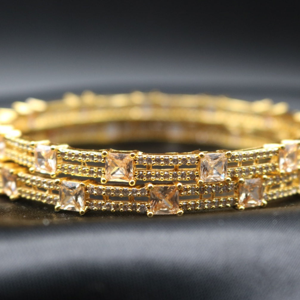 gold-plated bangles with champagne gemstones on a black surface 