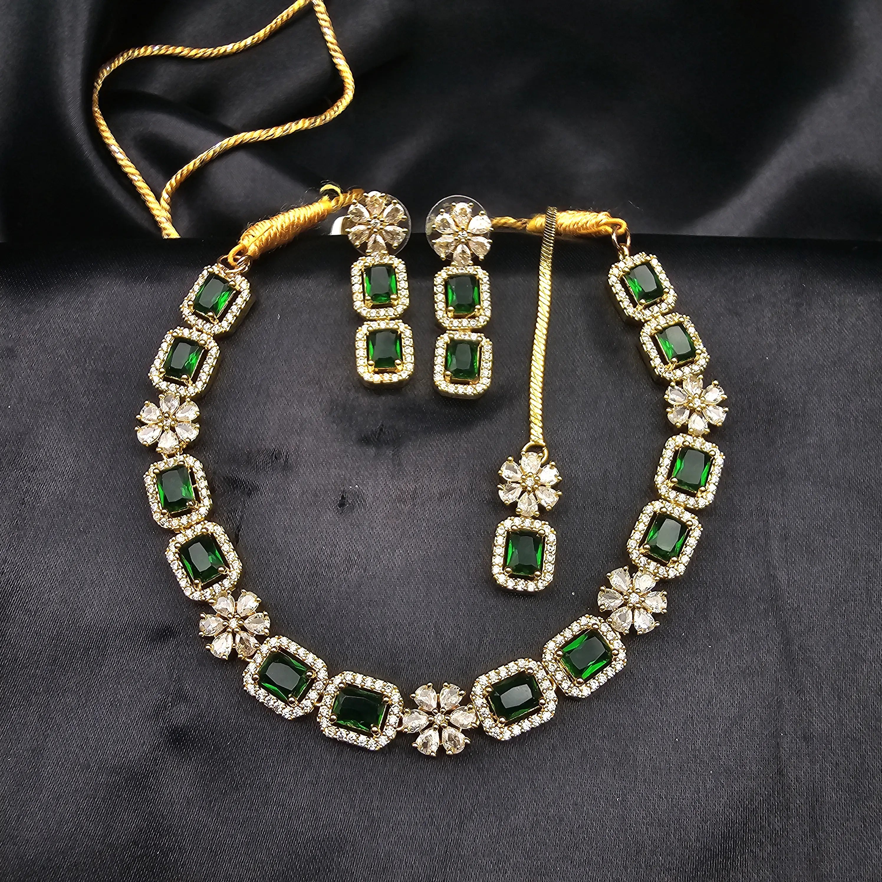 Matching necklace and earring set featuring emerald green cubic zirconia stones with American diamond borders.