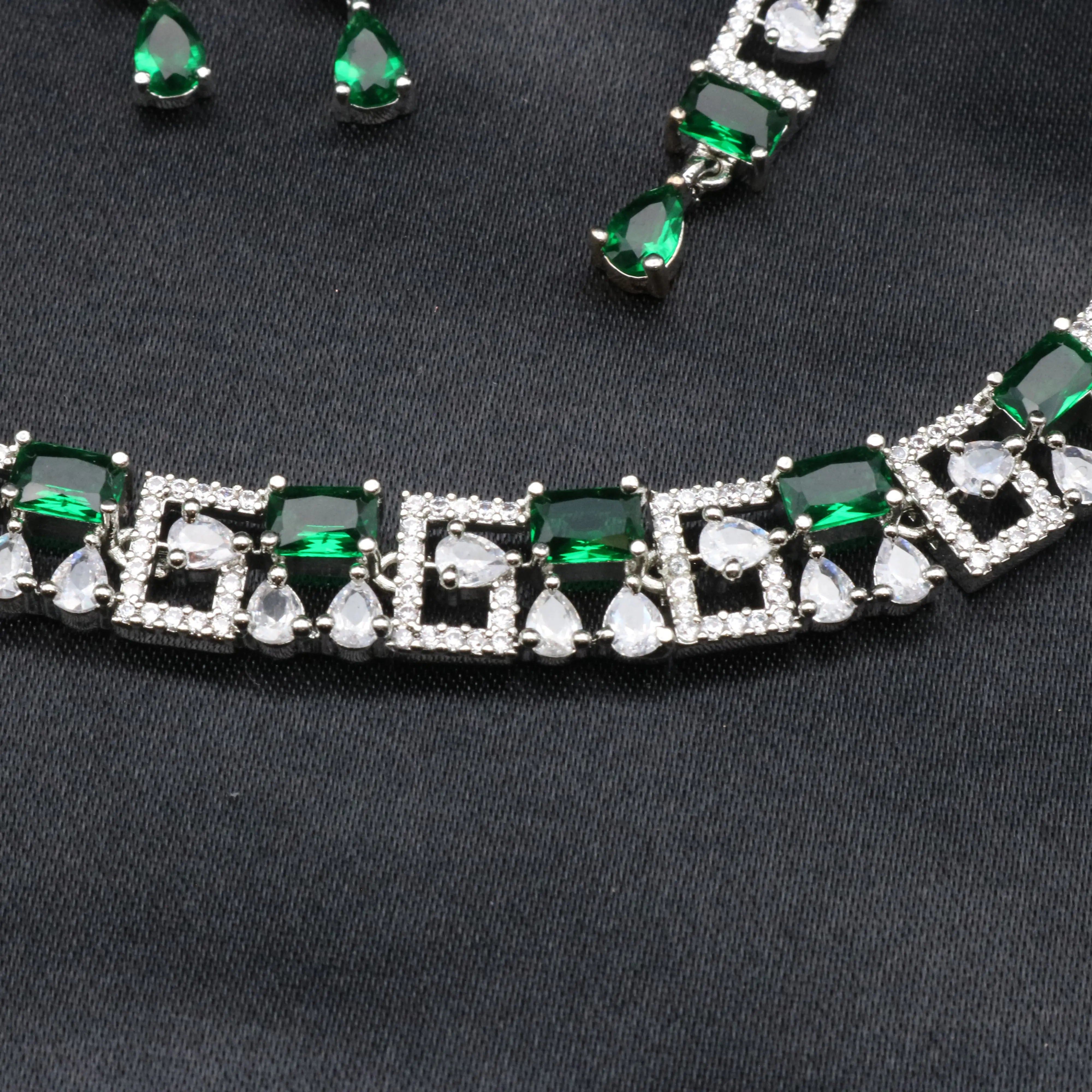 Close-up of emerald green and white CZ stones on Majesty necklace set with geometric frames.