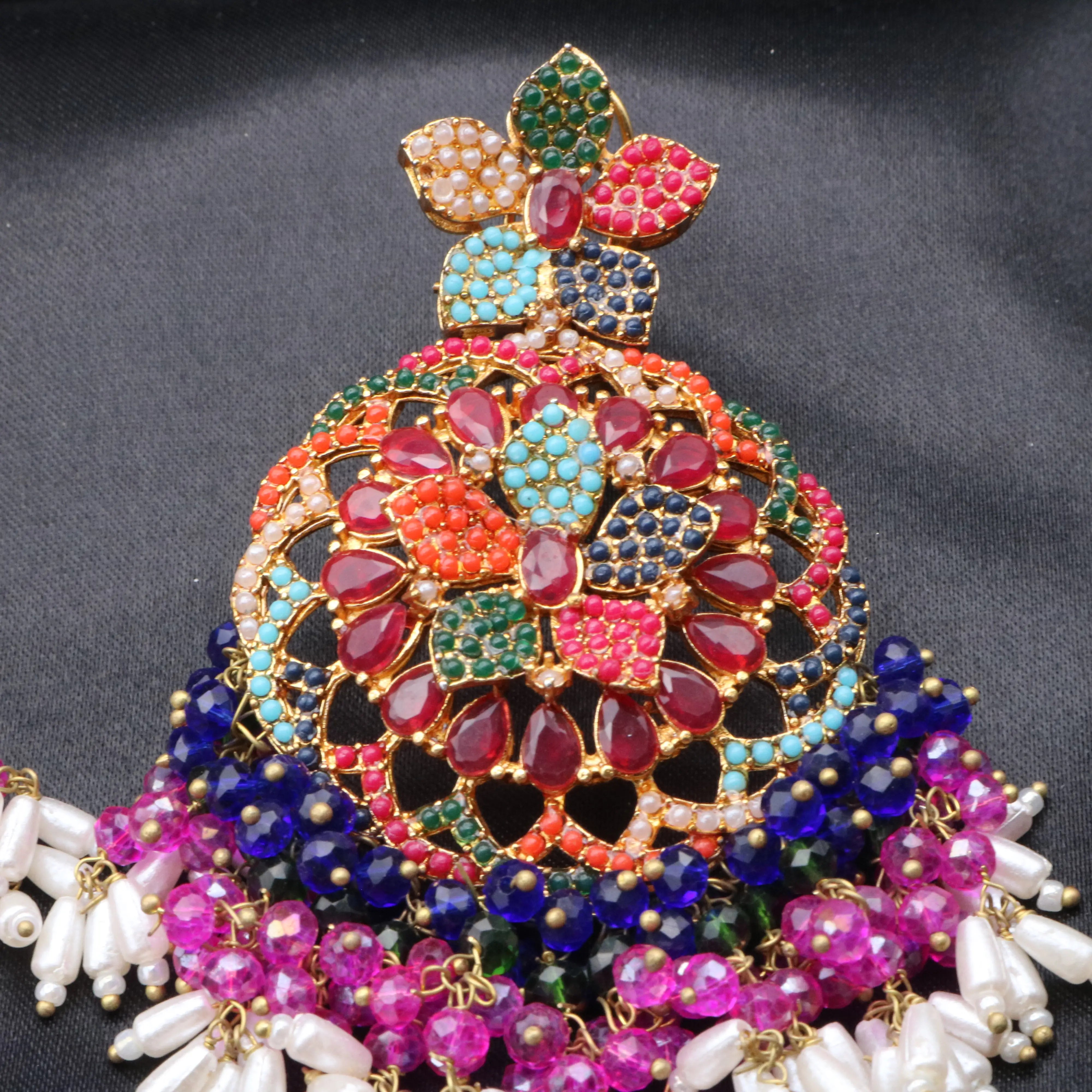 Colorful jewelry piece with gemstones and pearls on a dark background