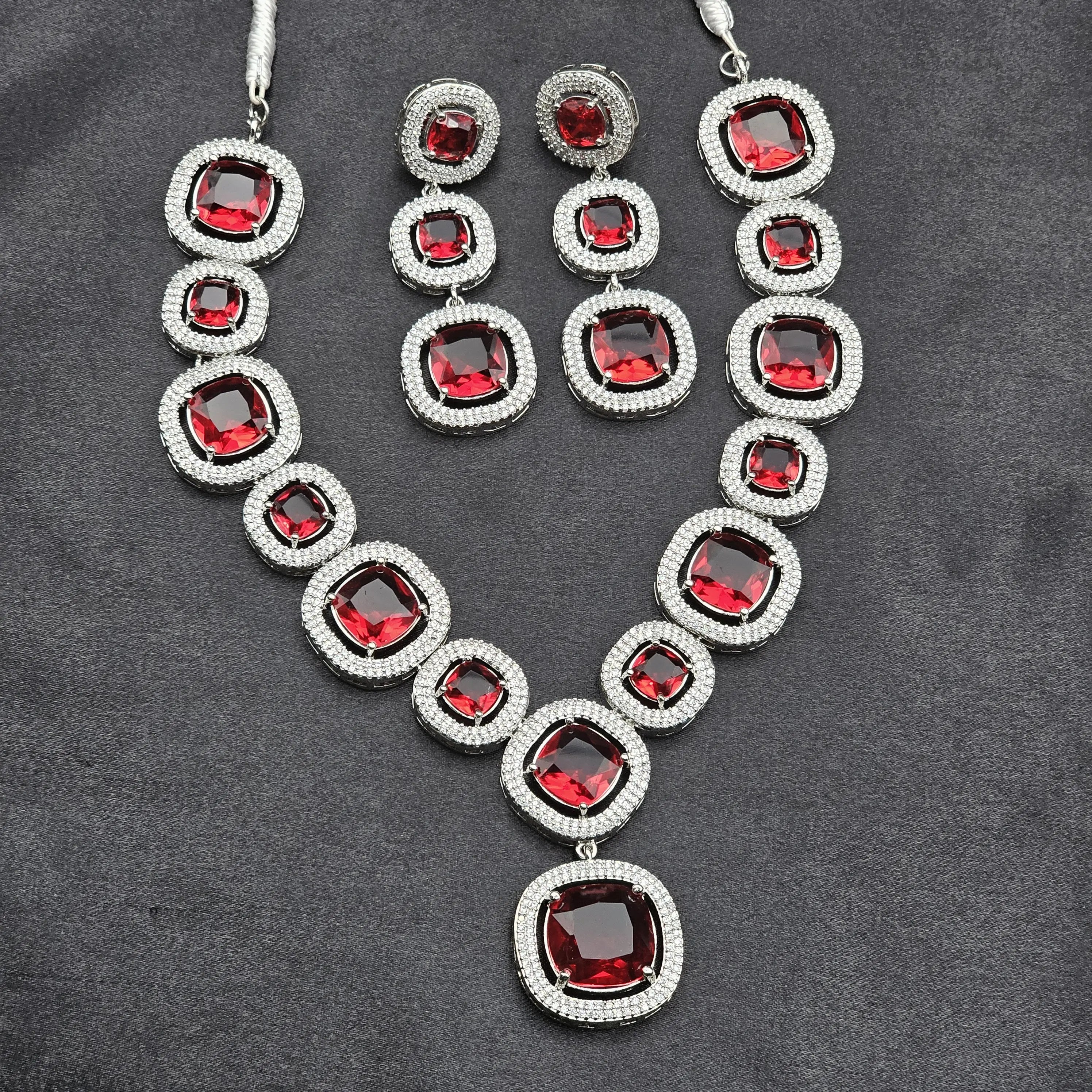 Red Pixie necklace and earrings set laid flat on black background