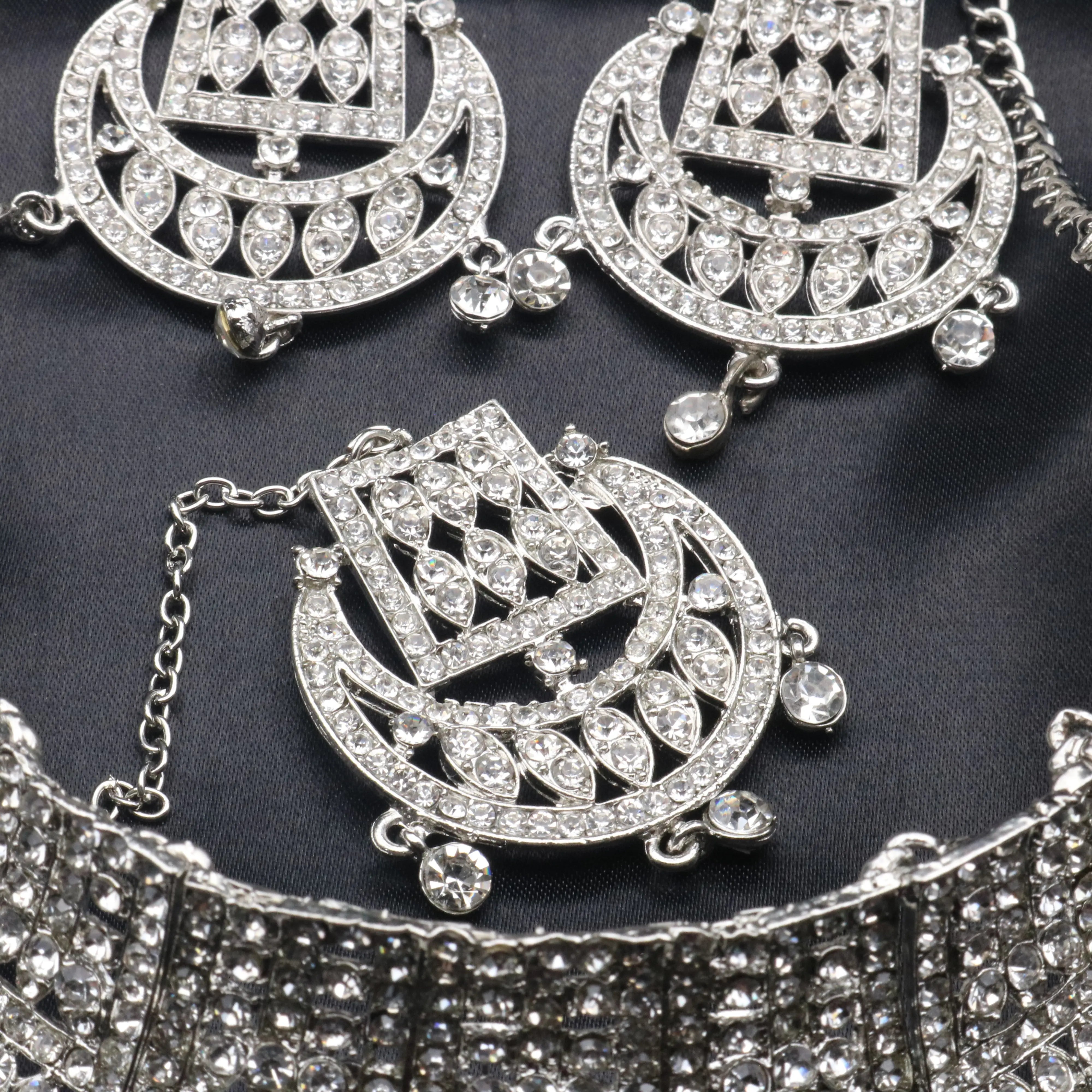 Close-up of Queen Necklace Set teeka and earrings with clear cubic zirconia stones on silver finish 