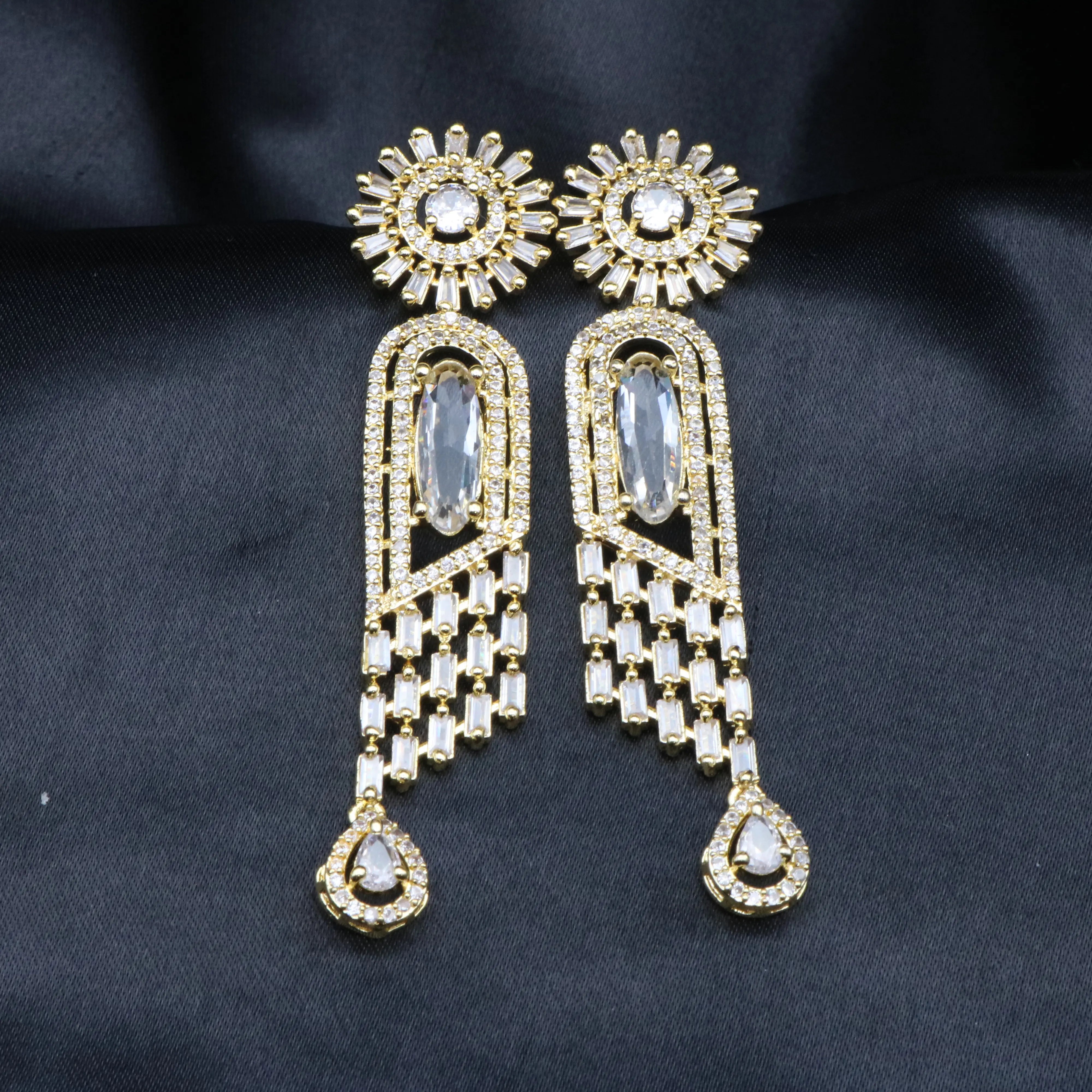 another view of a pair of stainless steel earrings featuring American Diamond accents and a clear gemstone, with a intricate geometric design.