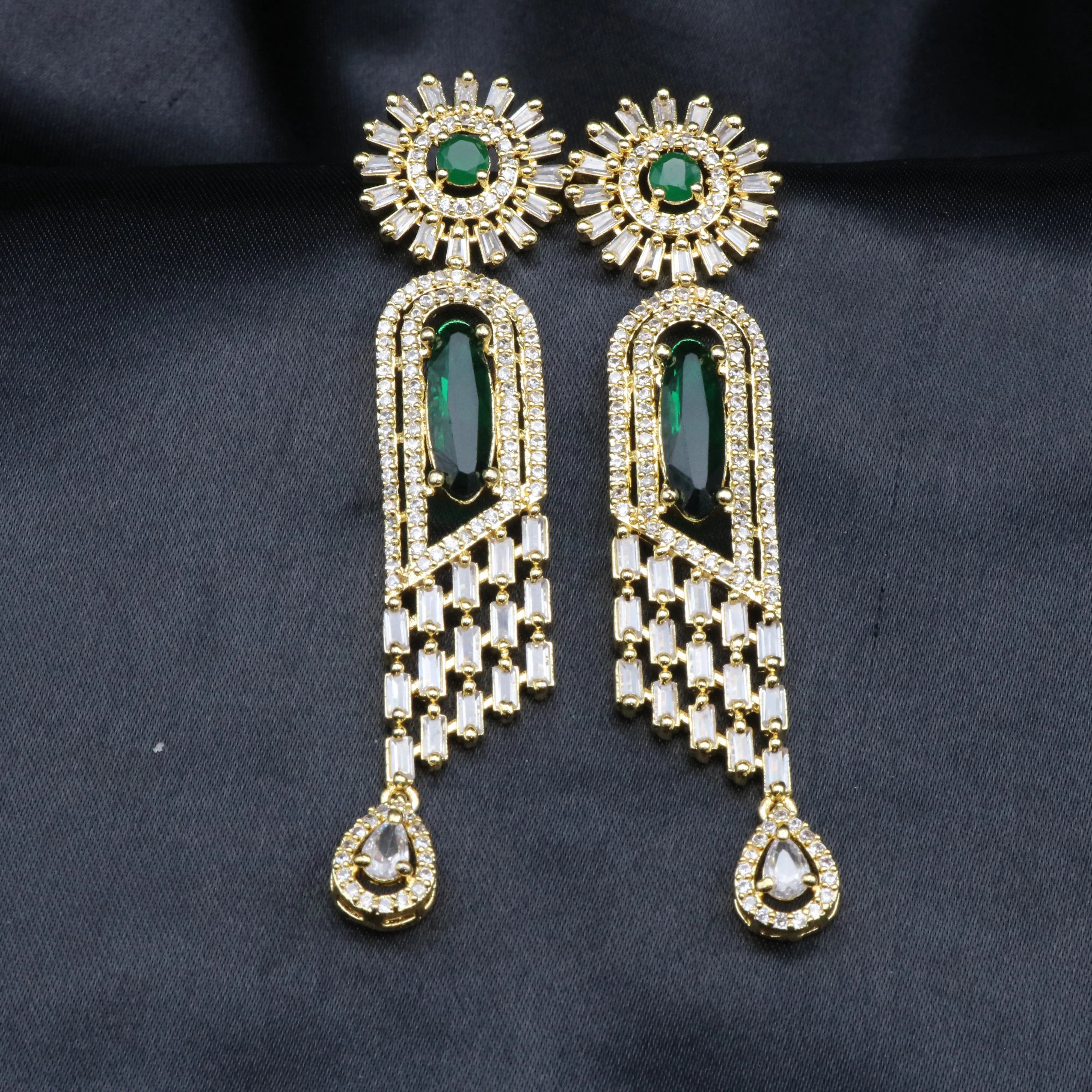 another view of a pair of stainless steel earrings featuring American Diamond accents and a green gemstones, with a intricate geometric design.