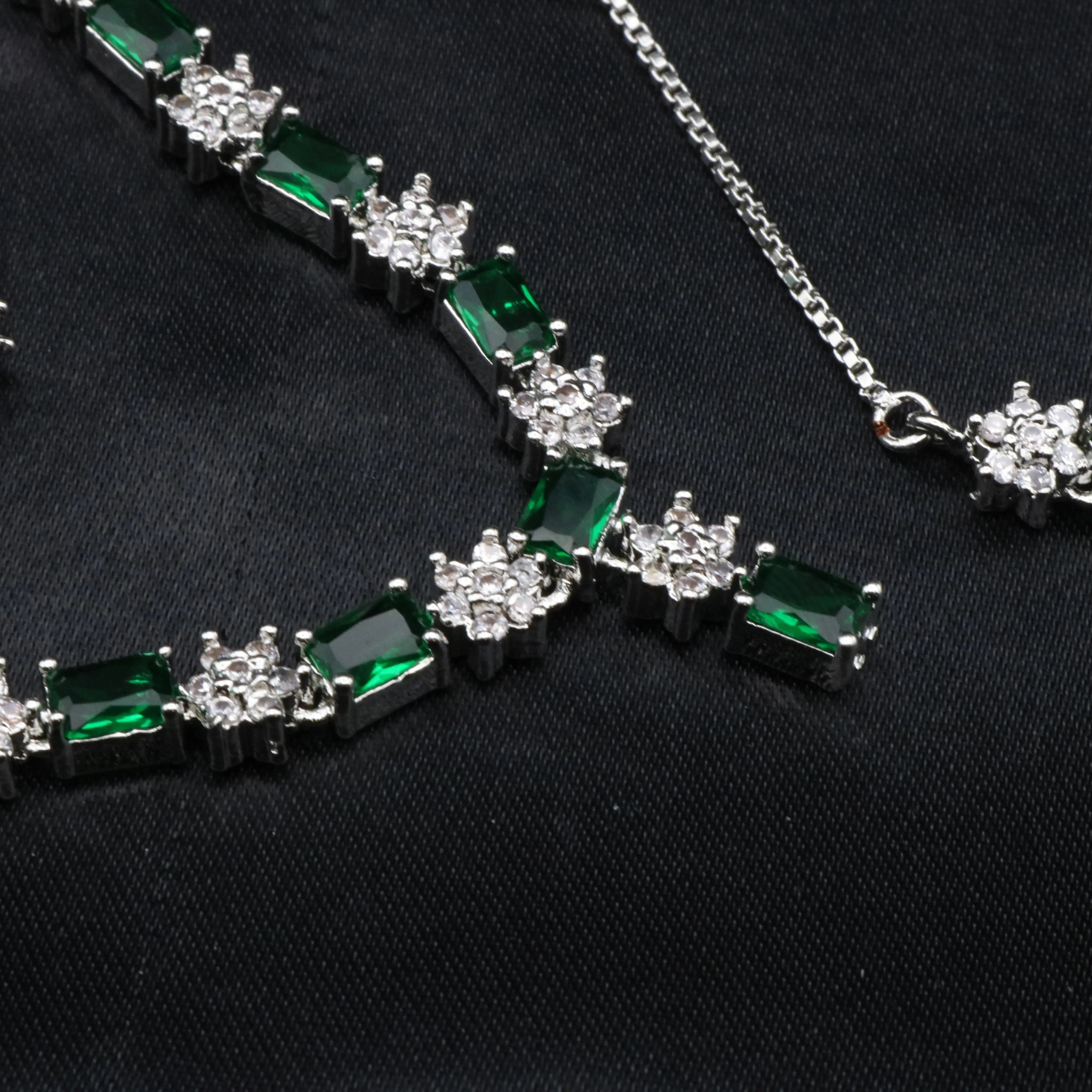Close-up of emerald green necklace segment featuring emerald-cut stones and round CZ clusters
