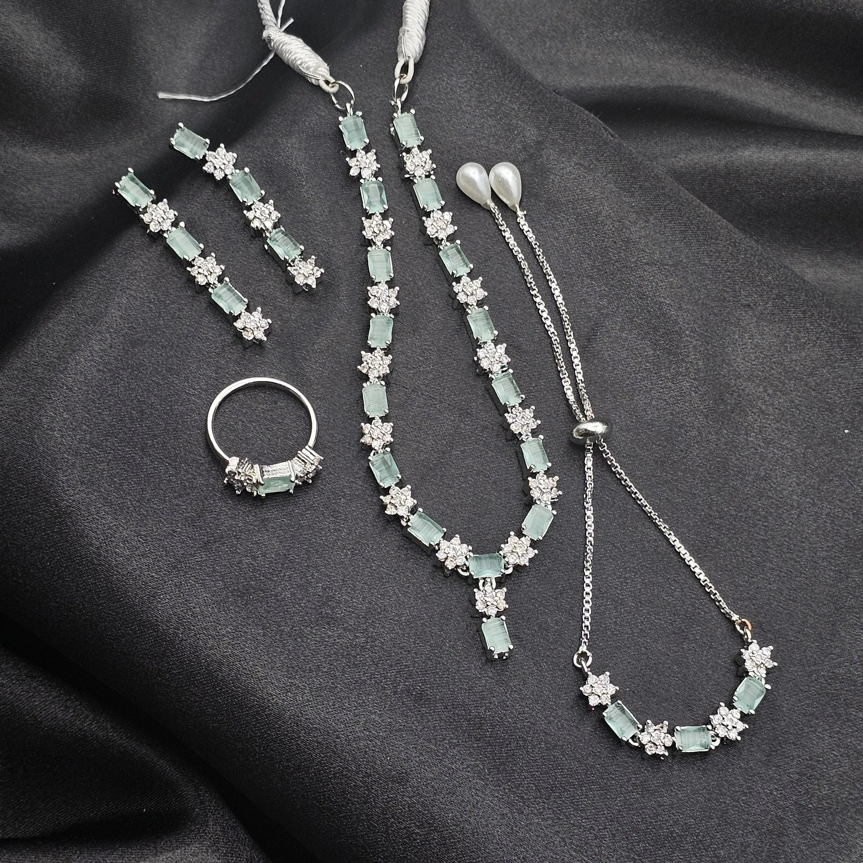 Reverie 5-piece necklace set in mint green with earrings, bracelet, ring, and teeka on black satin