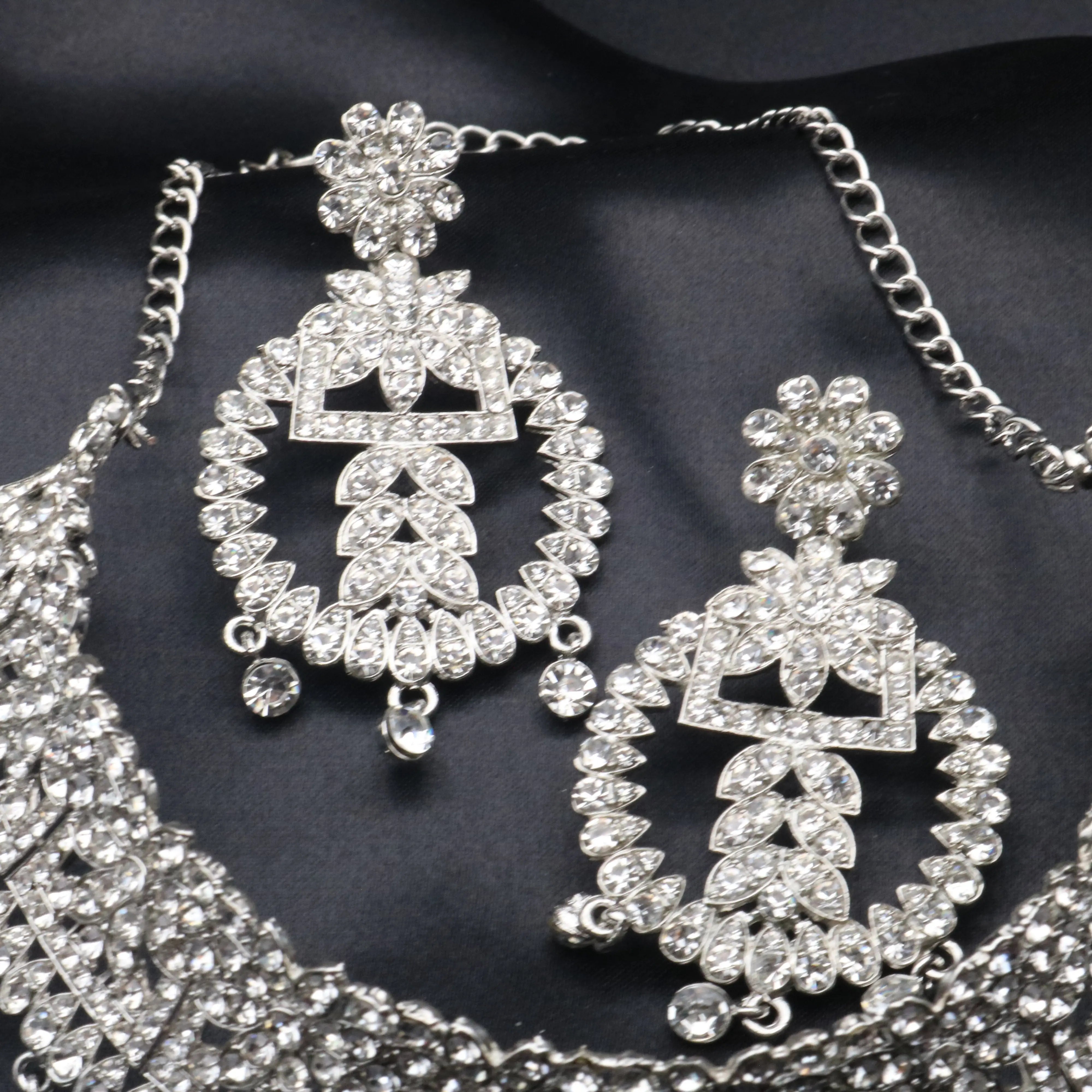 Close-up of Sage statement earrings featuring American diamonds in floral and geometric shapes