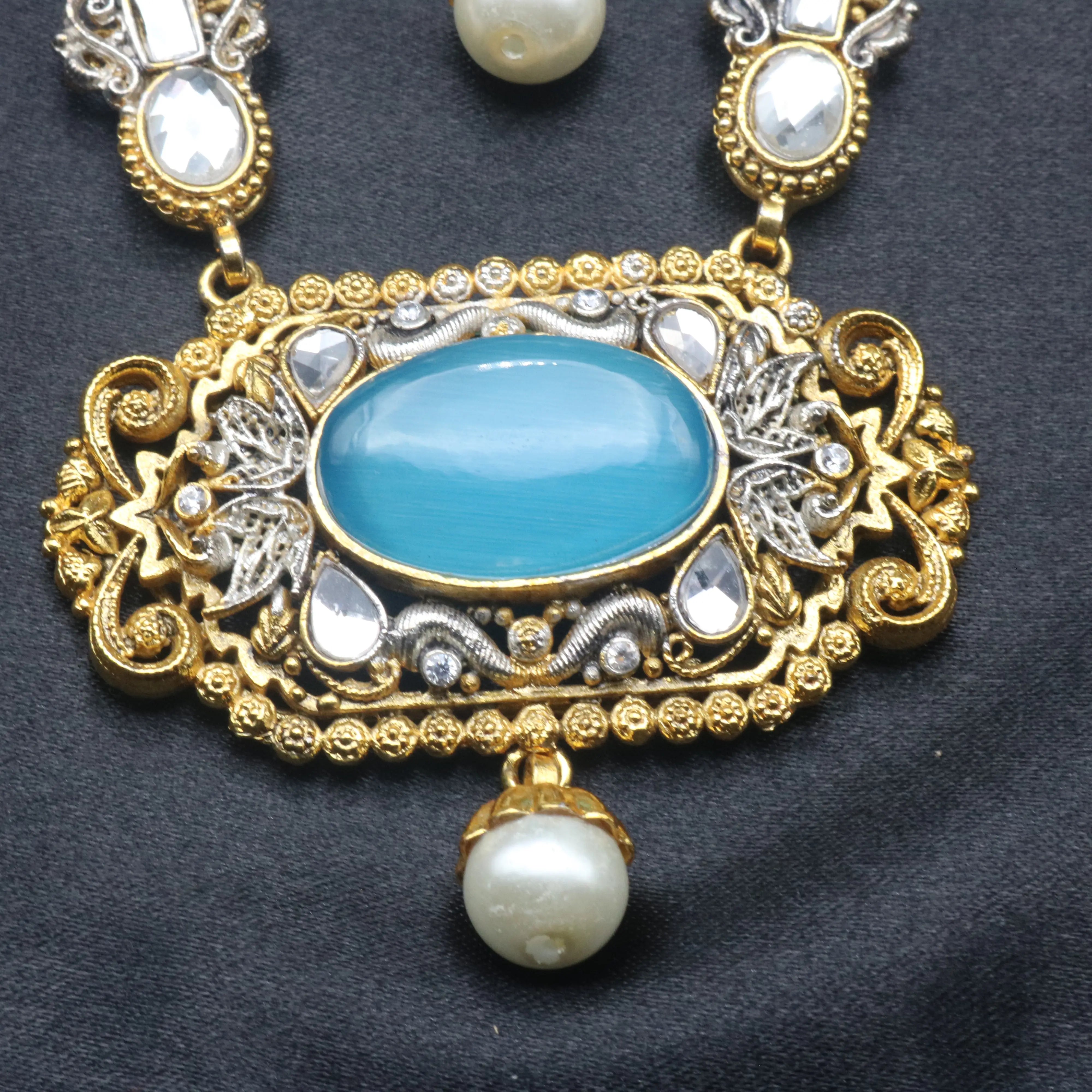 Close-up of the pendant centerpiece with aqua stone, kundan accents, and a single pearl drop
