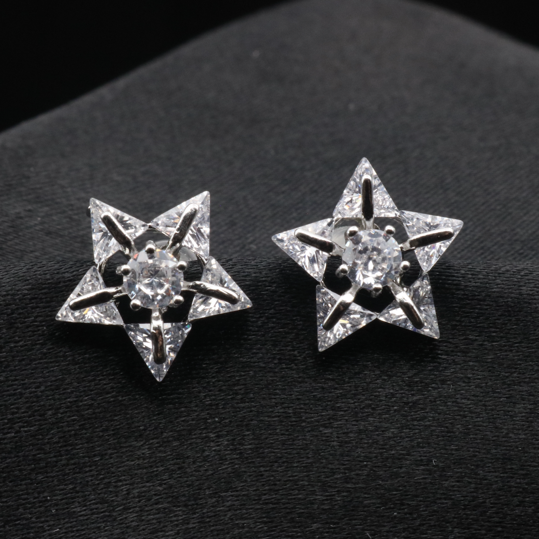 A pair of star-shaped earrings with American diamonds, displayed against a black background.