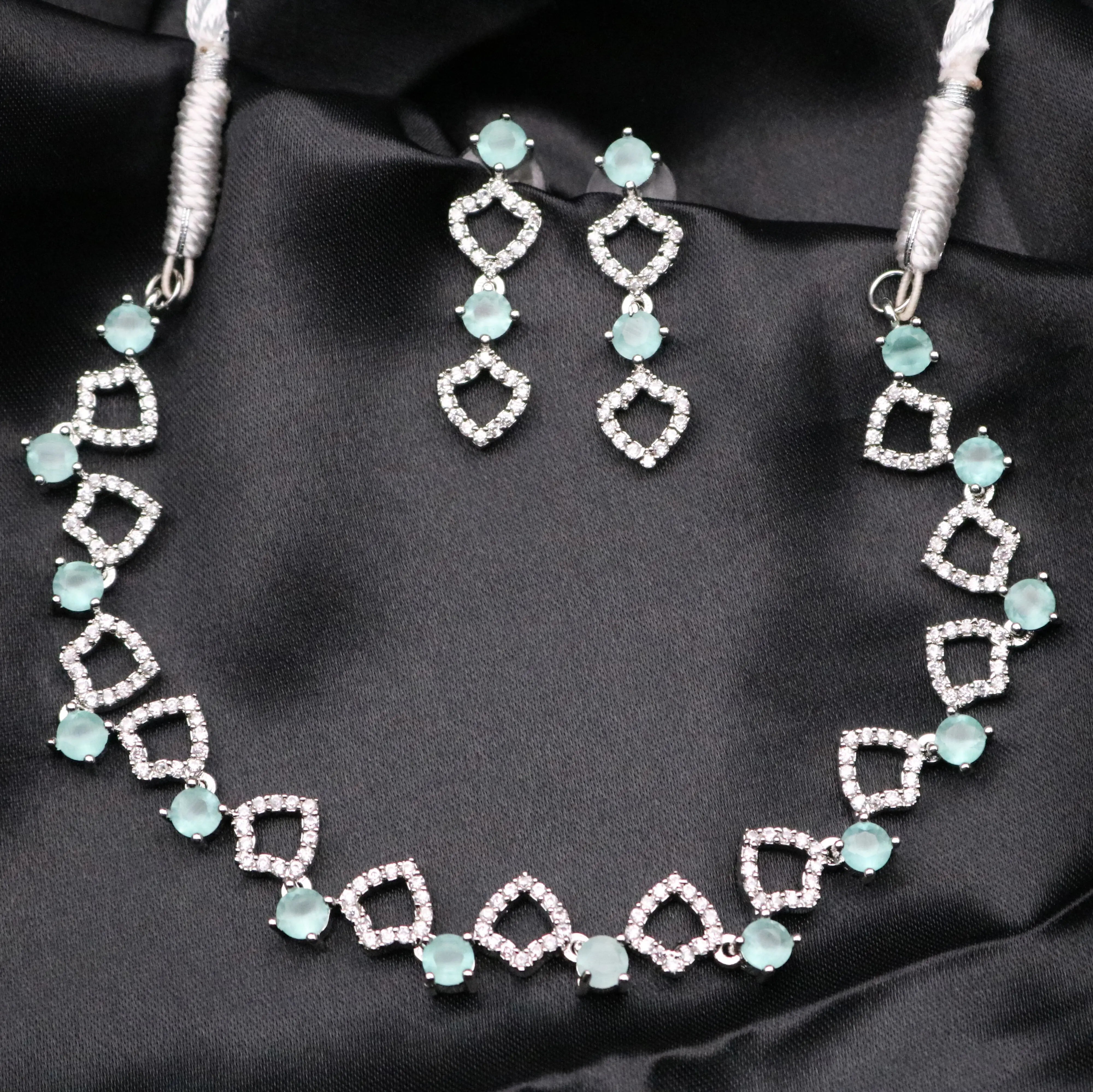 Starlight silver necklace set with mint gemstones and CZ earrings displayed on black satin