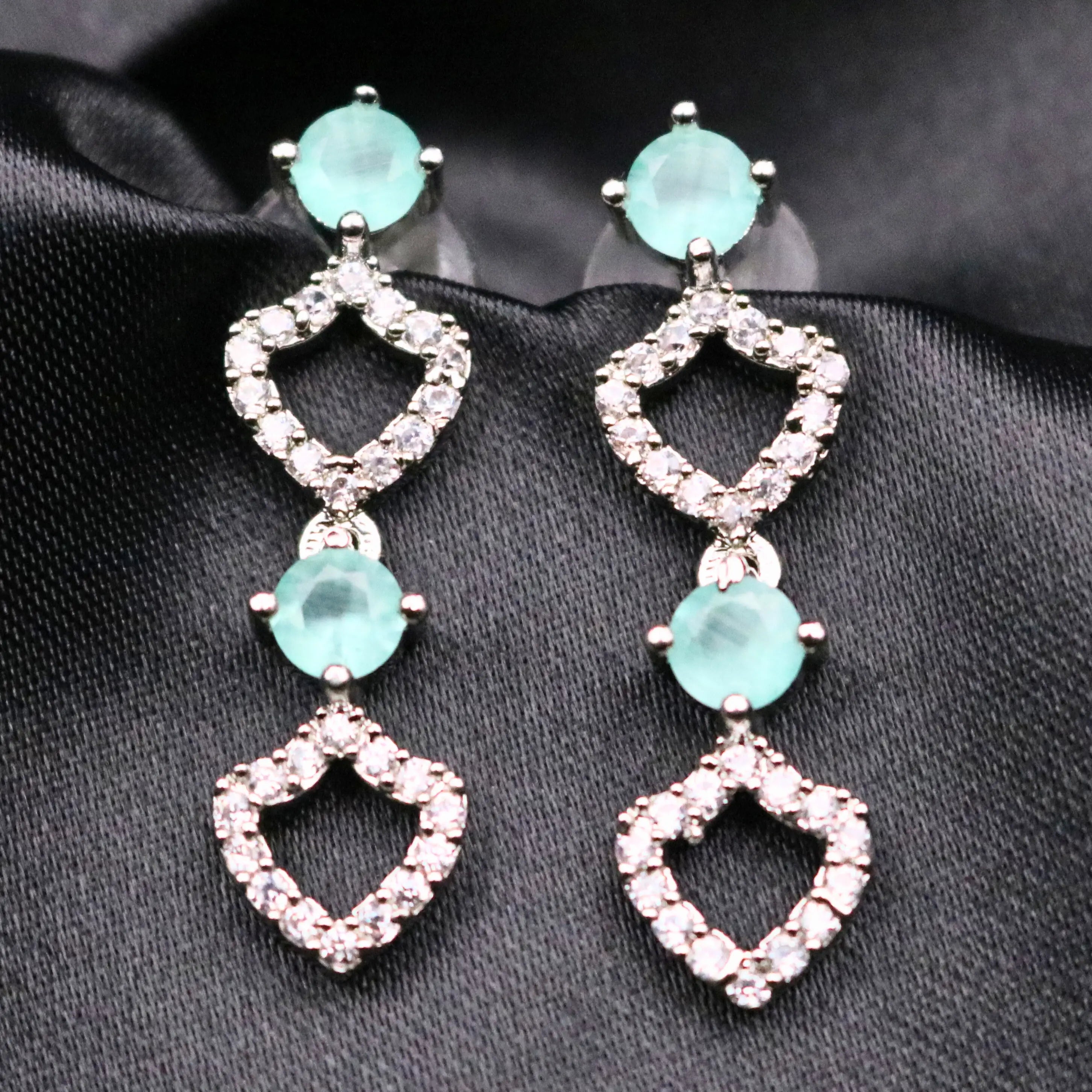 Close-up of Starlight earrings featuring mint stones and heart-shaped CZ frames