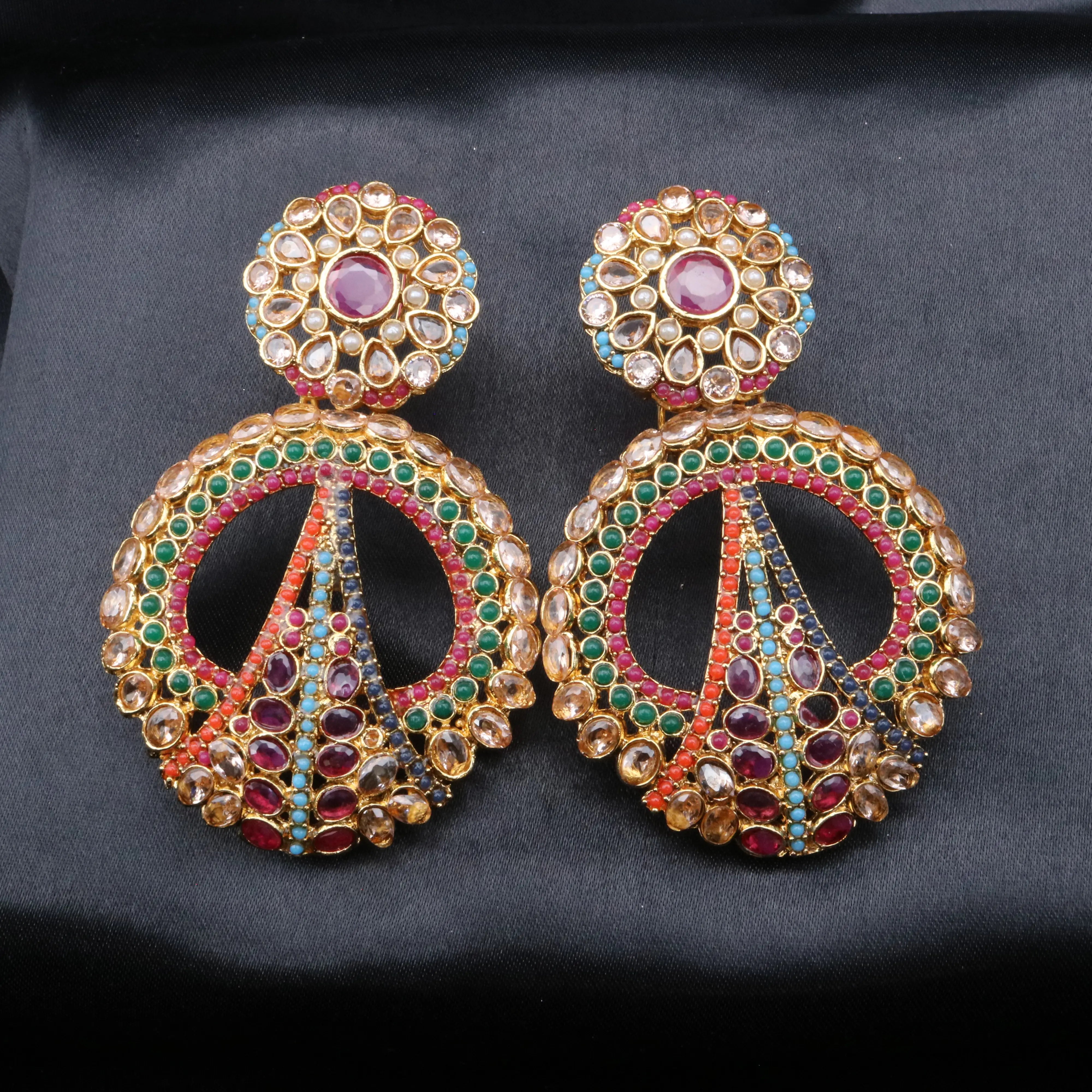 Pair of ornate earrings with gemstones on a dark background