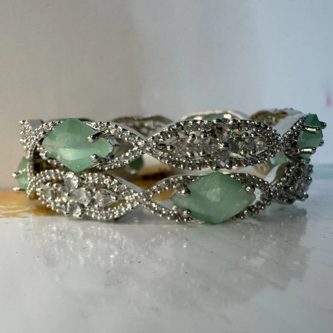 A pair of silver bangles adorned with turquoise rhinestones and American Diamond encrusted on a silver base.