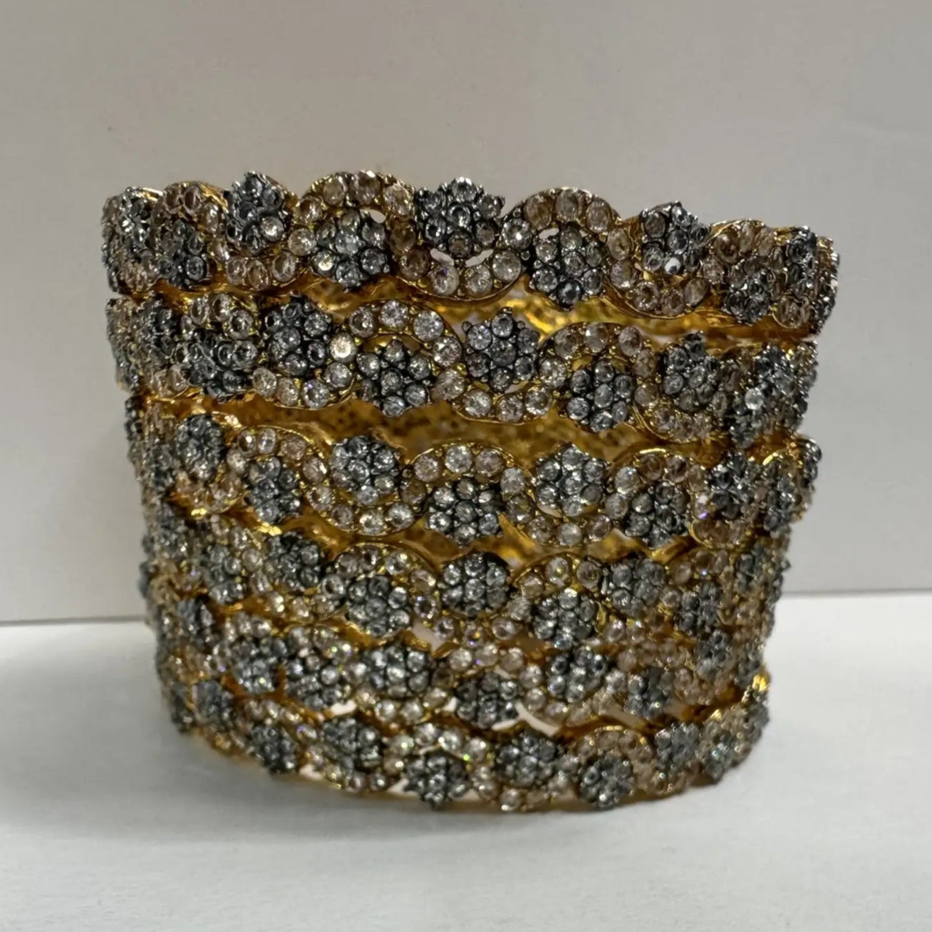 gold plated bangles with floral patterns with silver embellishments on a white background