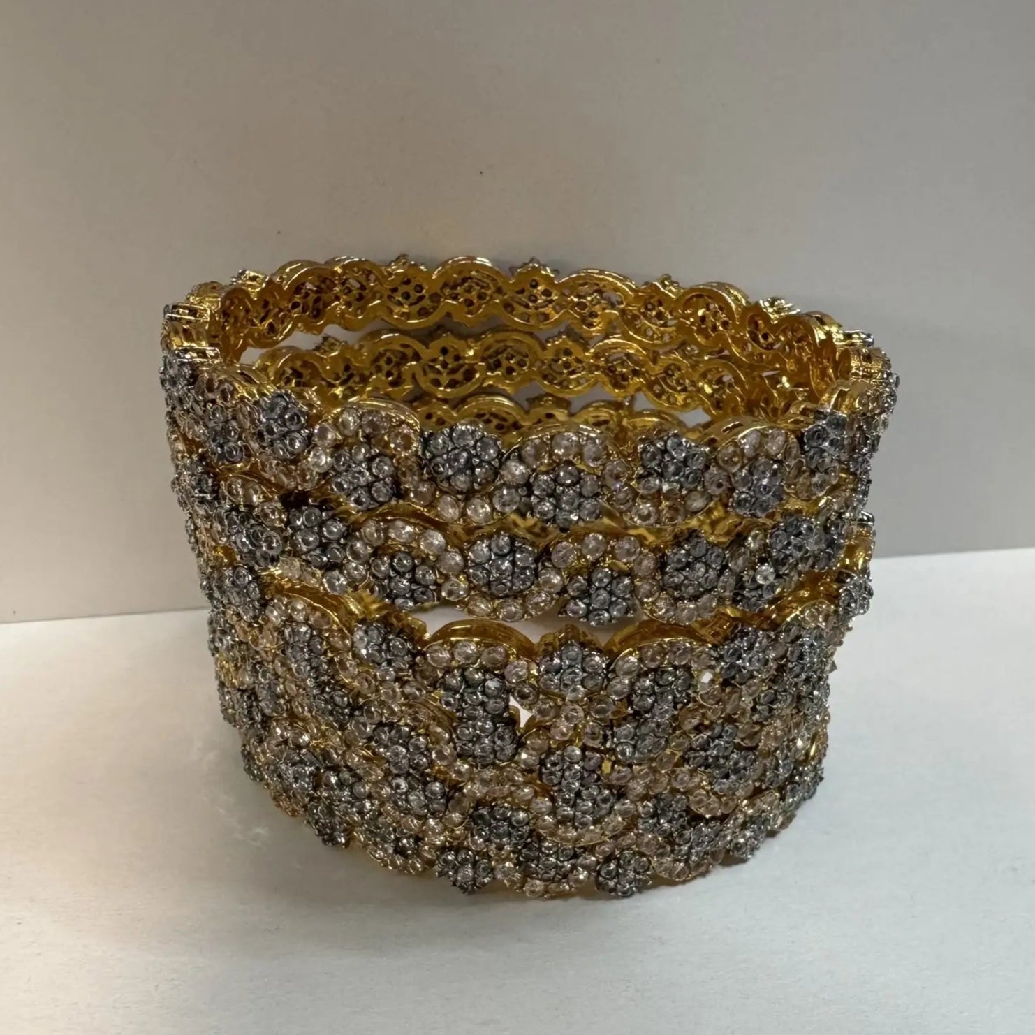 gold plated bangles with floral patterns with silver embellishments on a white surface