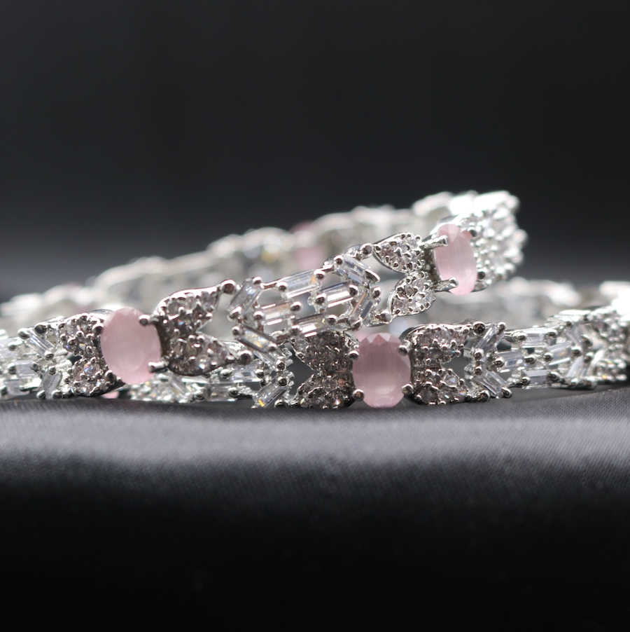 Stainless steel bangles adorned with sparkling American diamonds, and pink gemstones displayed against a dark background.