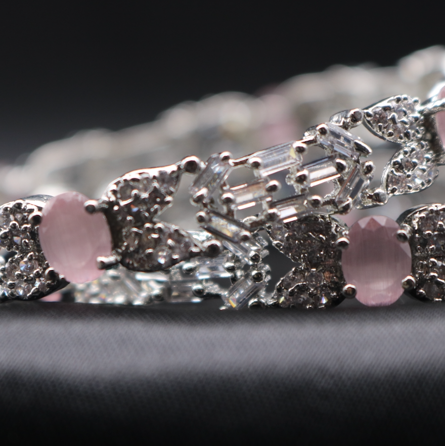 closer view of stainless steel bangles adorned with sparkling American diamonds, and pink gemstones displayed against a dark background.