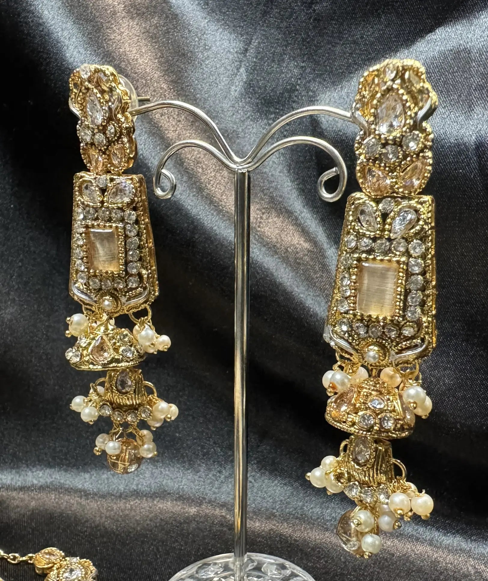 Side angle view of handcrafted gold earrings with American diamonds and pearl clusters