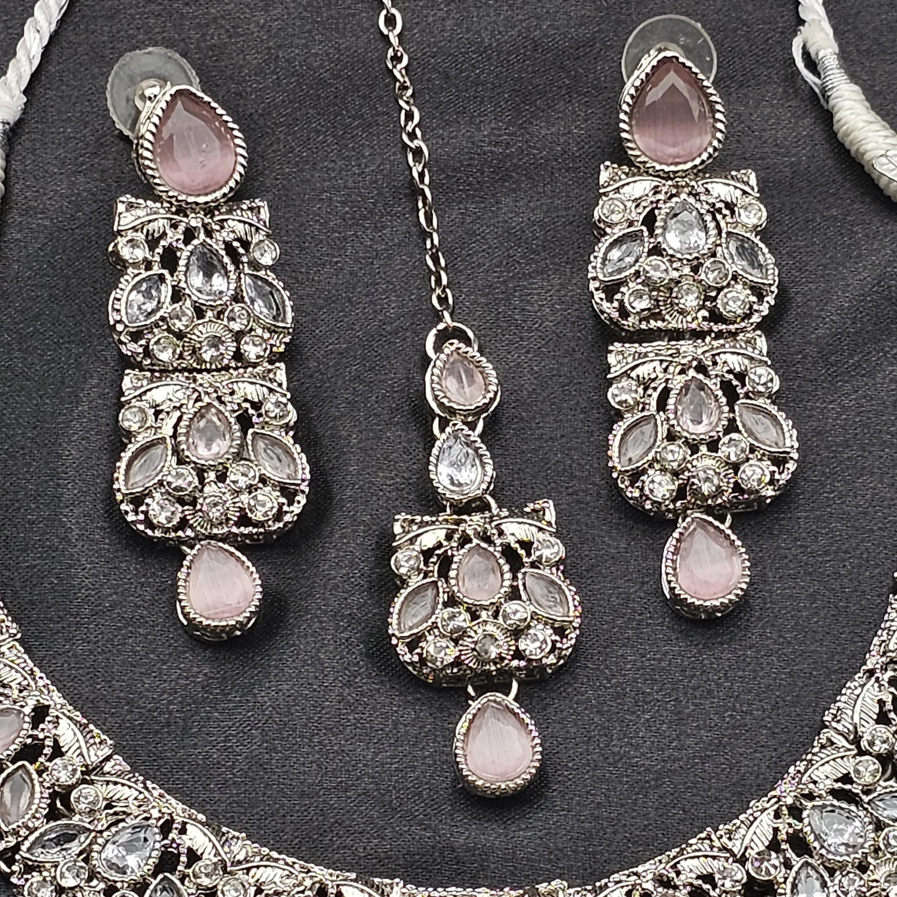 Close-up of Zahra pink and silver bridal earrings and teeka with CZ and gemstone-style pear drops