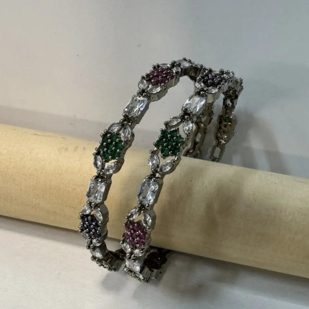 A multicolored diamond-encrusted bangles with vibrant hues of blue, green, and pink, set on a silver base, on a wooden stick