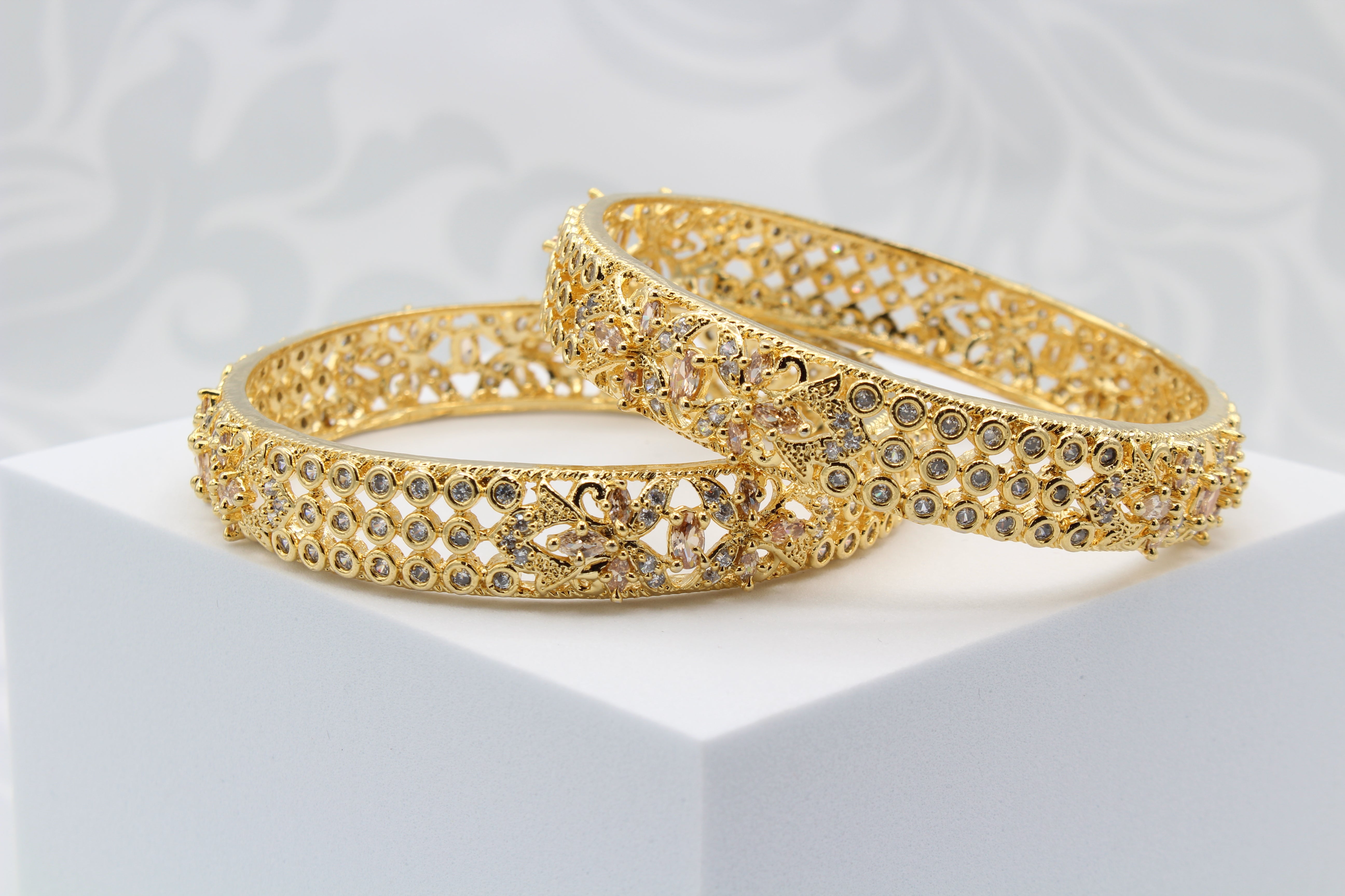 another view of Gold plated pair of bangles with shimmering shine and intricate design on a white surface